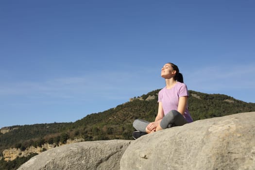 Sportswoman relaxing resting seated in the top of a cliff in the mountain a sunny day