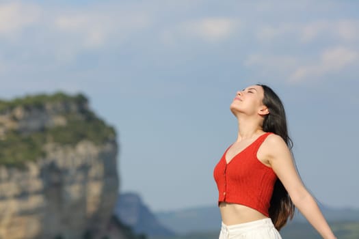 Mixed race woman in red breathing fresh air standing in the mountain