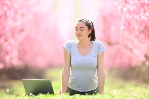 Front view portrait of a woman doing yoga guided online class in a field