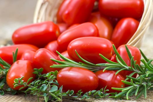 mini roma tomatoes and herbs on wooden background