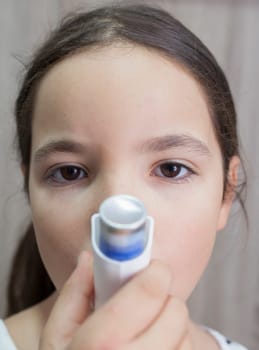 Child girl using medical spray for breath. Inhaler. Front view