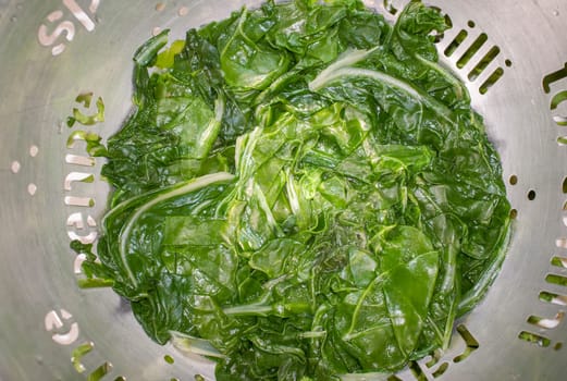 Boiled spinach on colander. Selective focus