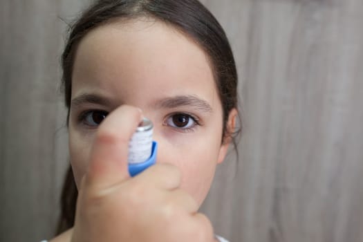 Child girl using medical spray for breath. Inhaler. Front view