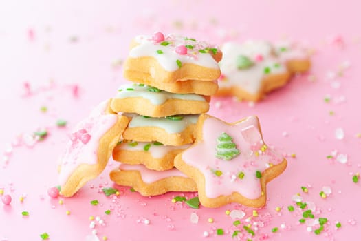 Colorful Christmas cookies with sugar sprinkles on a pink background
