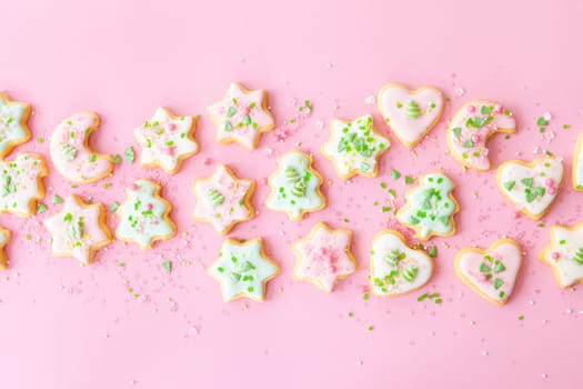 Colorful Christmas cookies with sugar sprinkles on a pink background