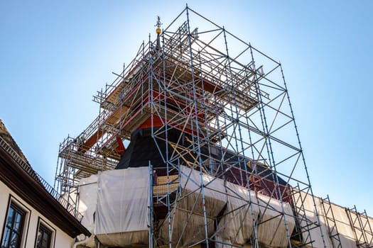 Church tower in scaffolding on a sunny day with bright sky.