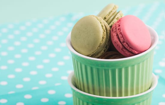 Sweet Macarons with green bowls and green fabric background