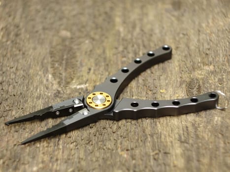 pliers with sharp nippers and narrow jaws on wooden background close-up