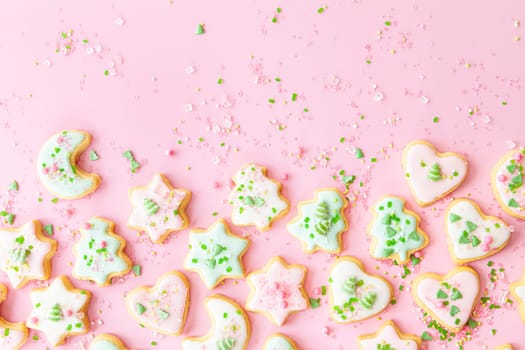 Colorful Christmas cookies with sugar sprinkles on a pink background