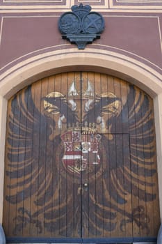 The historic Adlertor on the facade of the Fuggerei in Augsburg shows the coat of arms of an imperial double-headed eagle. It is a listed building.