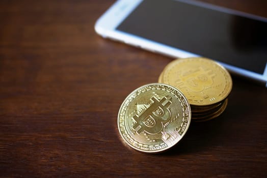 stack of Physical Bitcoins with smartphone virtual currency concept on wooden background