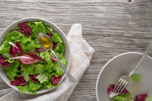 Healthy red and green lettuce salad meals on wooden table background. Eating fresh radicchio and young lettuce with dressing sauce