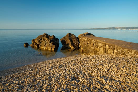 Bathing place with piled up gravel on the actually rocky coast of Krk in Croatia