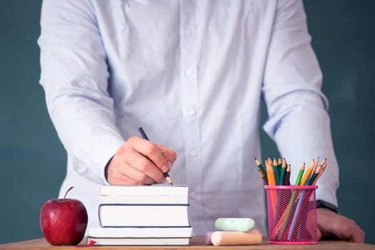 Back to school concept: teacher giving books to her studens in the classroom at the begining of the new school season.