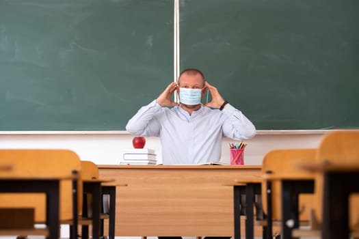 Teacher with mask teaching how to wear mask at school. Social distanting and classroom safety during coronavirus epidemic