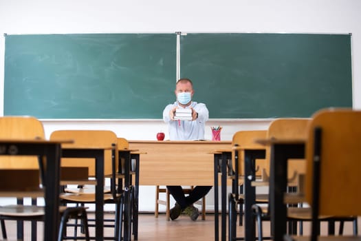 Teacher with mask in the classroom. Social distanting and classroom safety during coronavirus epidemic