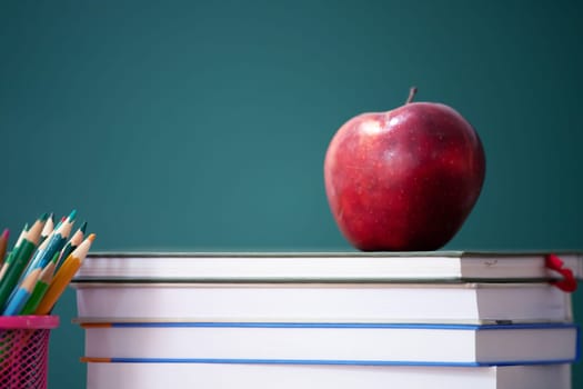 Back to School Concept. Apple, accessories and books against chalkboard.
