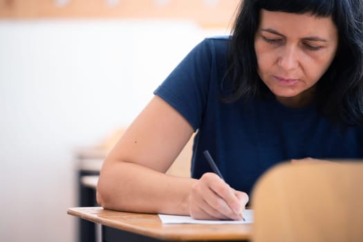 High school or university student holding pencil writing on paper answer sheet. Final exam concept.