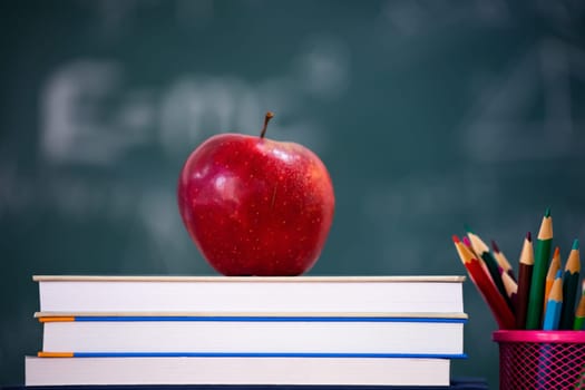 Back to School Concept. Apple, accessories and books against chalkboard.