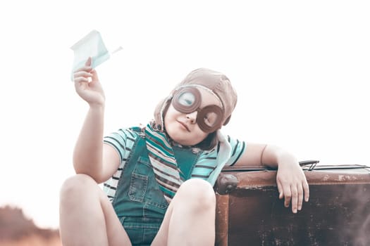 Happy kid playing in pilot helmet pretend to be aviator. Travel, vacation and freedom concept. Childhood, imagination, dream.
