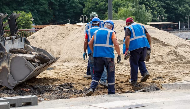 the road workers in blue uniforms and helmets on the pavement
