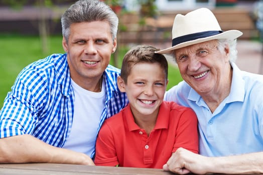 Happy senior man, young man and boy looking at camera