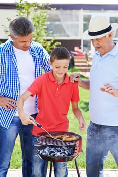 Modern senior man, young man and boy cooking barbecue