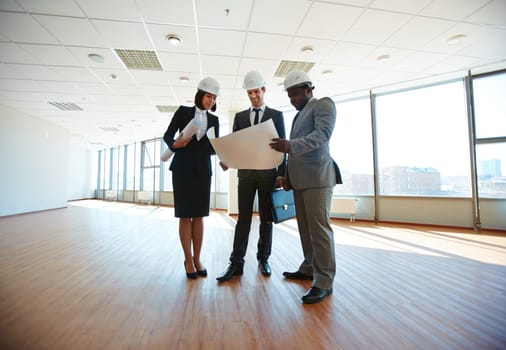 Group of architects discussing blueprint in office