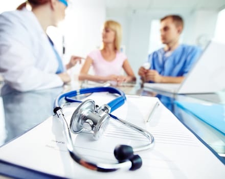 Prescription paper and stethoscope on background of young doctors working