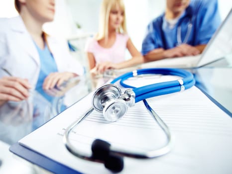 Prescription form and stethoscope on background of working practitioners
