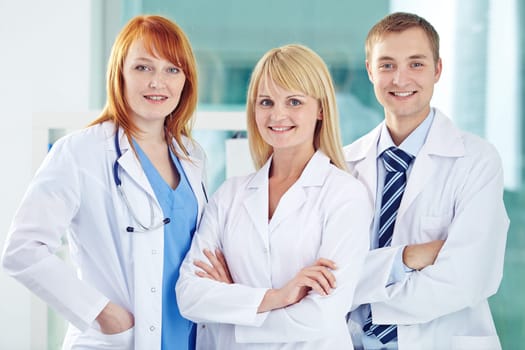 Happy young colleagues in white coats looking at camera