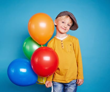 Cute lad with multi-color balloons looking at camera
