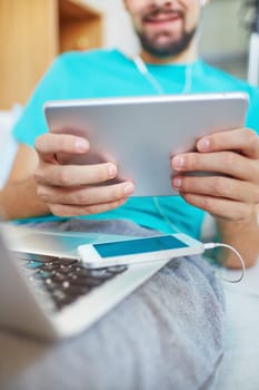 Young man using laptop, touchpad and smartphone at leisure