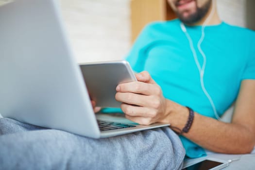 Male hands holding digital tablet over open laptop