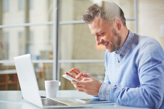 Happy manager writing sms in office