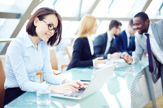 Pretty employee typing on laptop in working environment