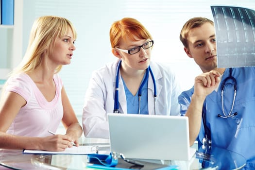 Portrait of young doctor commenting x-ray to his colleagues