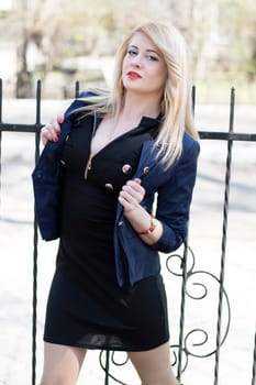 portrait of the young woman at an iron fence, in park