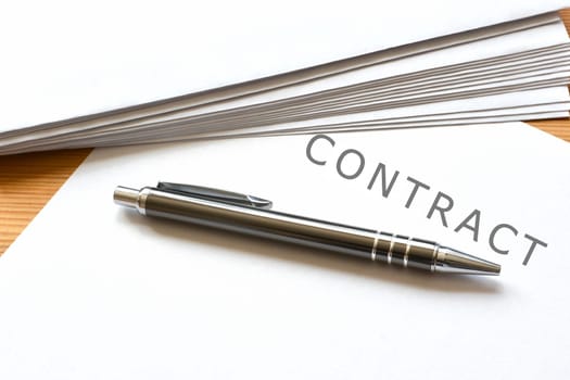 a contract and a ballpoint pen are on a desk