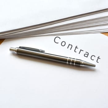 a contract and a ballpoint pen are on a desk
