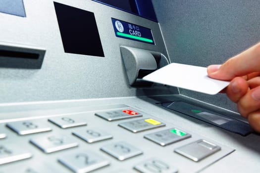 male hand businessman inserts credit card into the ATM and withdraws money