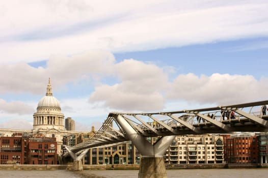 London,United Kingdom – March 31,2015: Visitors and passers-by walk across the modern steel structure of the Millennium Bridge with St. Paul's Cathedral at its end on March 31,2015 in London.