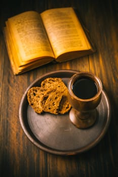 The sacrament of holy communion - bread, wine and bible on wooden table
