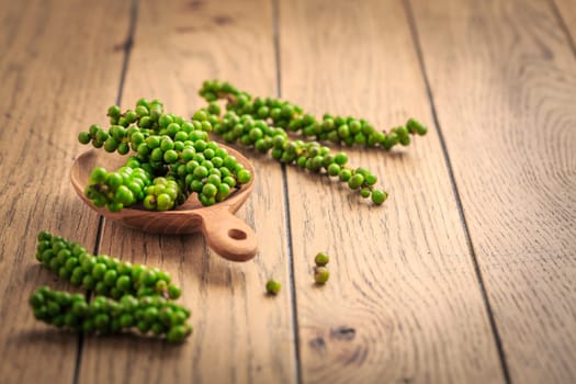 Fresh green peppercorns on wooden kitchen table.