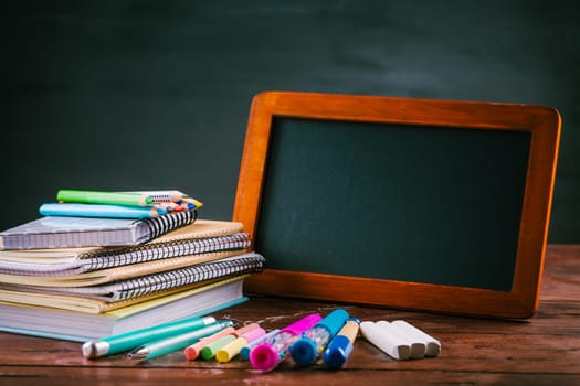 Pile of book and exercise books with school applies and apple snack with chalkboard. Back to school concept.