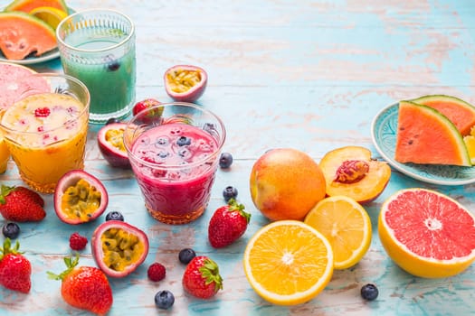 Variation of smoothies and refreshing drinks with fresh fruits for hot summer on blue background