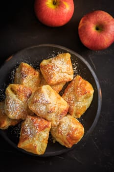 Homemade small apple turnovers in bowl on black background