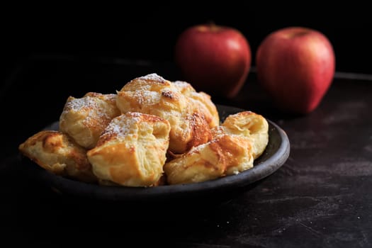 Homemade small apple turnovers in bowl on black background