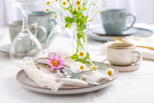 Spring and summer place setting with fresh flowers, cutlery and coffee cup