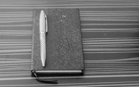 Pen and notebook on office table. Table top view. Corporate business background.